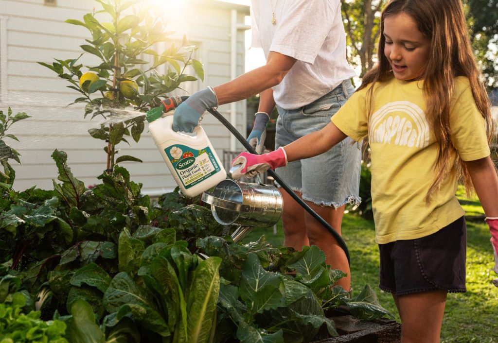 Woman and girl watering their garden.