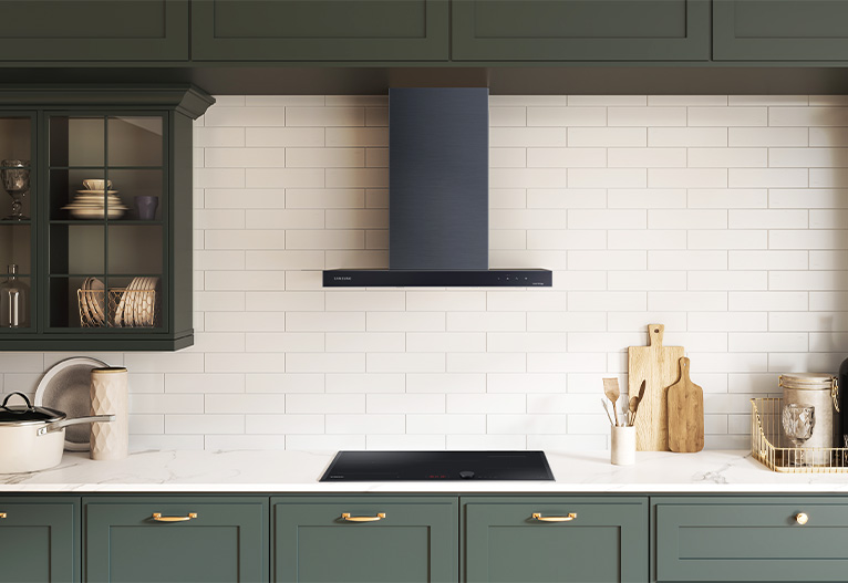 Kitchenwith black rangehood, green cabinets and white tiles.