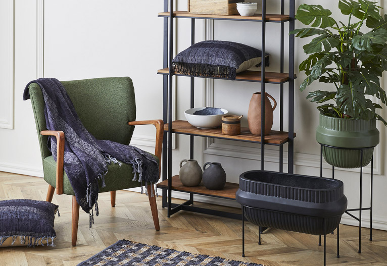 Green mid-century modern armchair next to an open bookshelf.