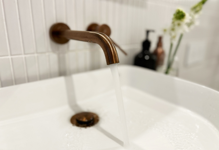 Water runs from a bathroom tap into a white basin.