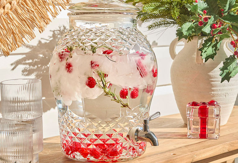 Glass drinks dispenser filled with berries.