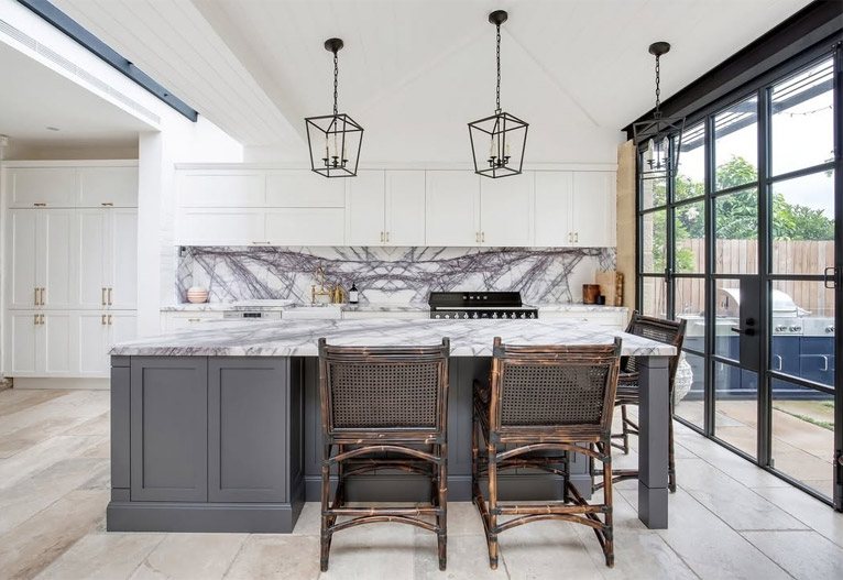 Hamptons-style kitchen with grey island bench and metal pendant lights.