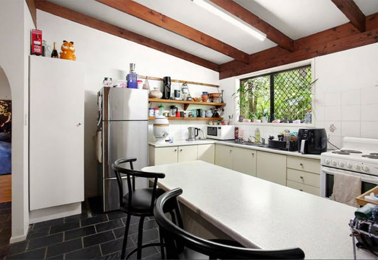 Dated kitchen with exposed beams and slate floor.