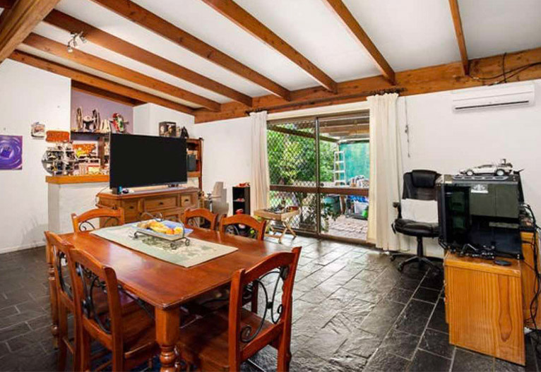 Dated family living room with exposed beams and slate floor.