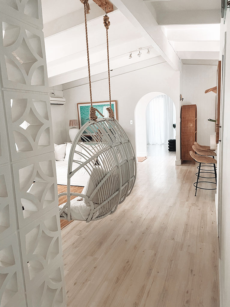 Light, coastal living room with hanging chair.