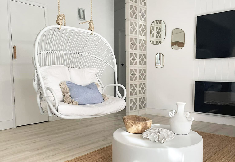 Coastal living room with white rattan hanging chair.