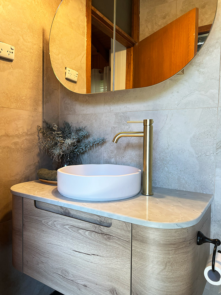 Renovated ensuite with curved timber cabinet.