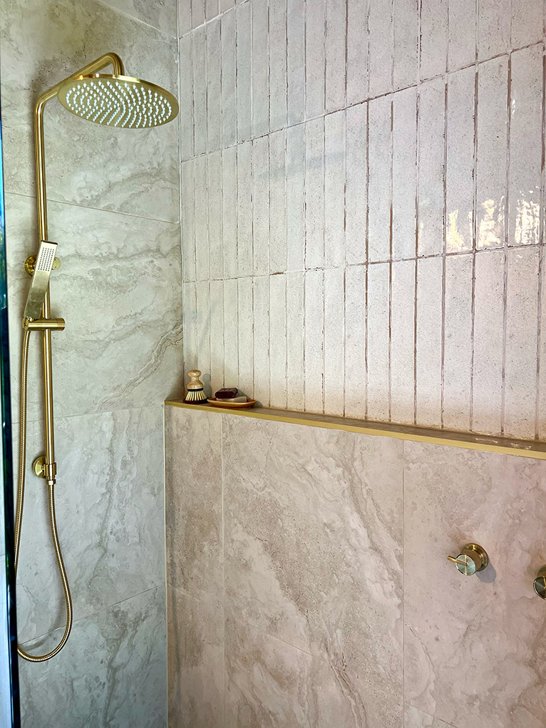 Renovated ensuite shower with horizontal tiles and gold tapware.