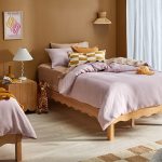 Wooden single beds with scalloped edges dressed with pink quilt covers.