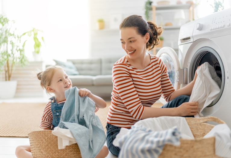 Mother and child filling a washing machine.