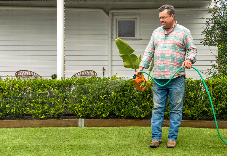 Jason Hodges fertilising lawn with Charlie Carp liquid fertiliser.