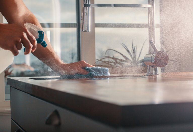 Person cleaning a kitchen bench.