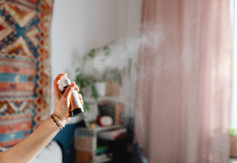 Person spraying essential oils in a room.