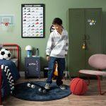 Tween boy playing with a skateboard in his bedroom.