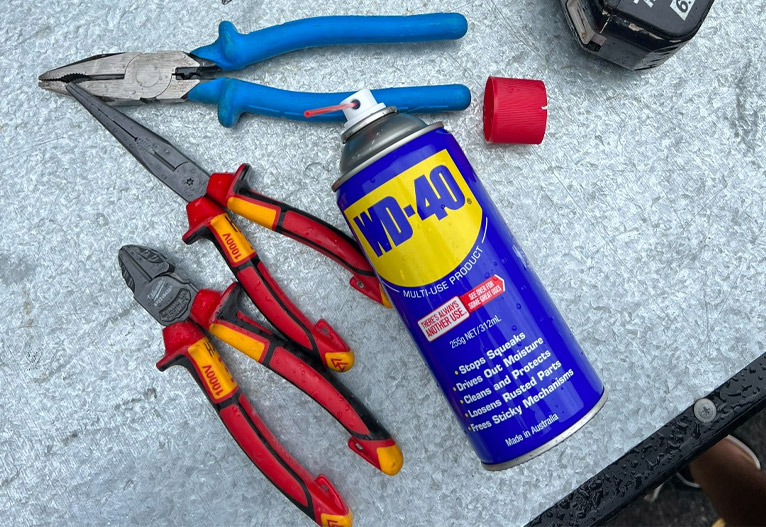 A can of WD-40 on a bench next to some tools.