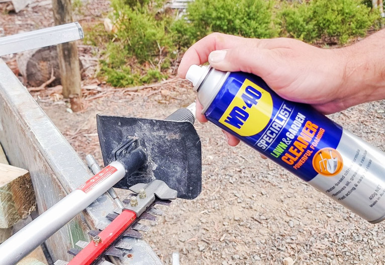 Person use a can of WD-40 on garden tools.