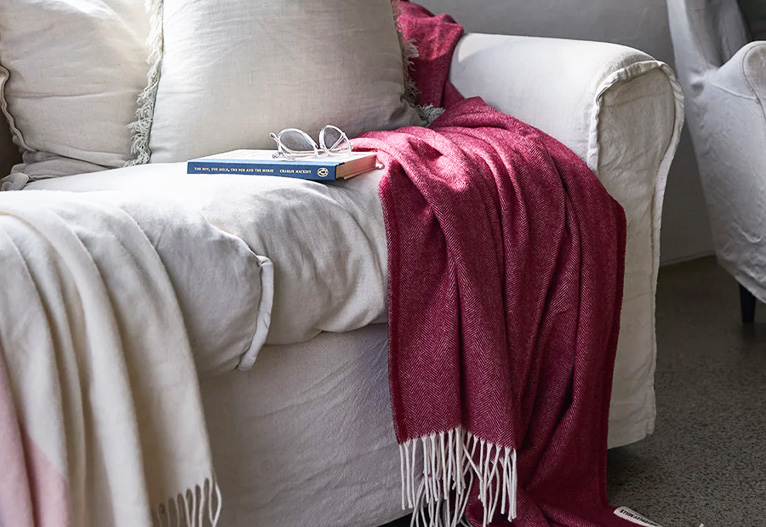 Waverley Mills burgundy merino wool blanket on a white sofa.