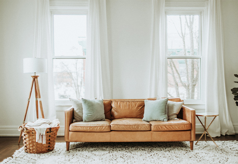 Living room with tan sofa and sheer curtains.