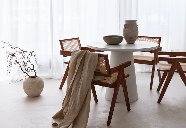 Dining area with round table and white sheer curtains.
