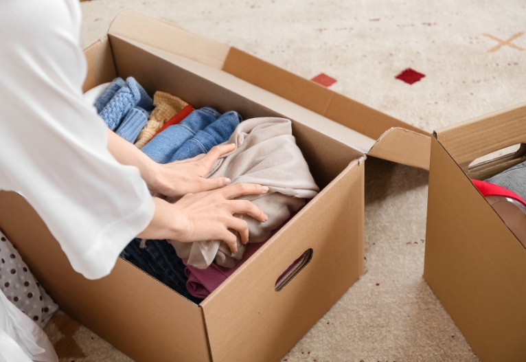 Person packing box with clothes.
