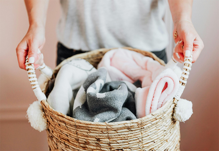 Person holding a basket of blankets.