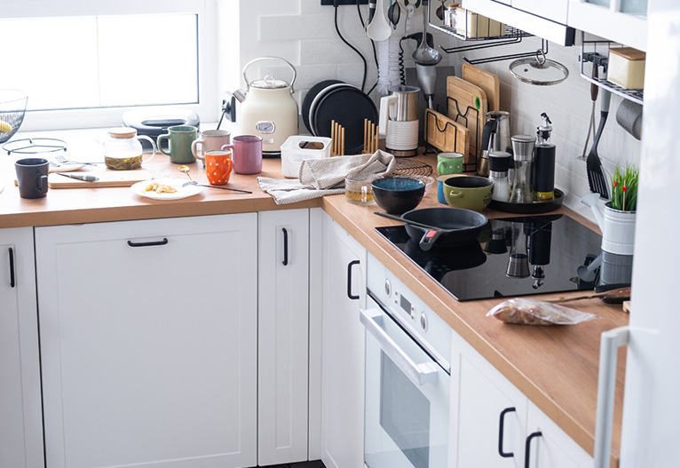 A messy kitchen with cluttered benchtops.