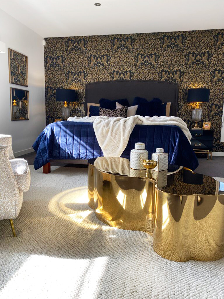 Luxurious master bedroom with navy bedding and feature gold wallpaper.
