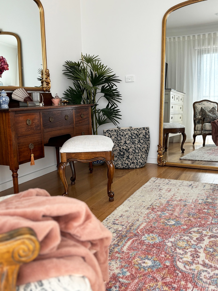 Gold-framed mirrors and antique furniture in a small bedroom.