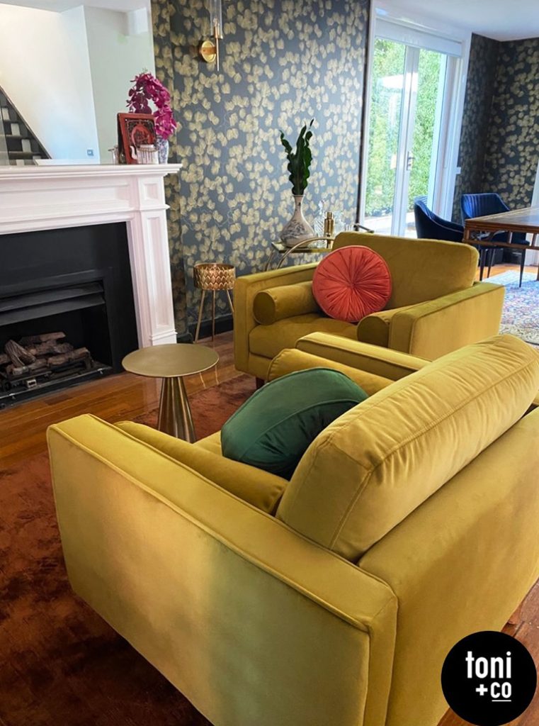 Living room with mustard armchairs and feature wallpaper.