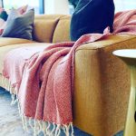 Mustard sofa with red throw blanket.