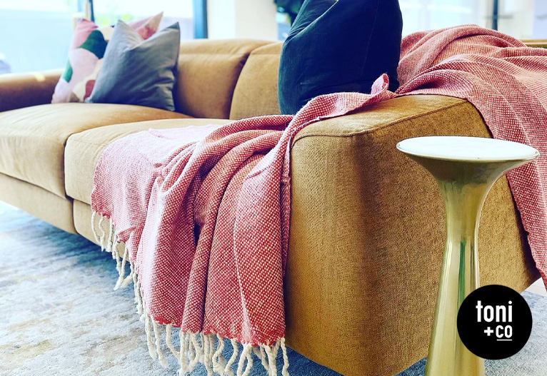 Mustard sofa with red throw blanket.