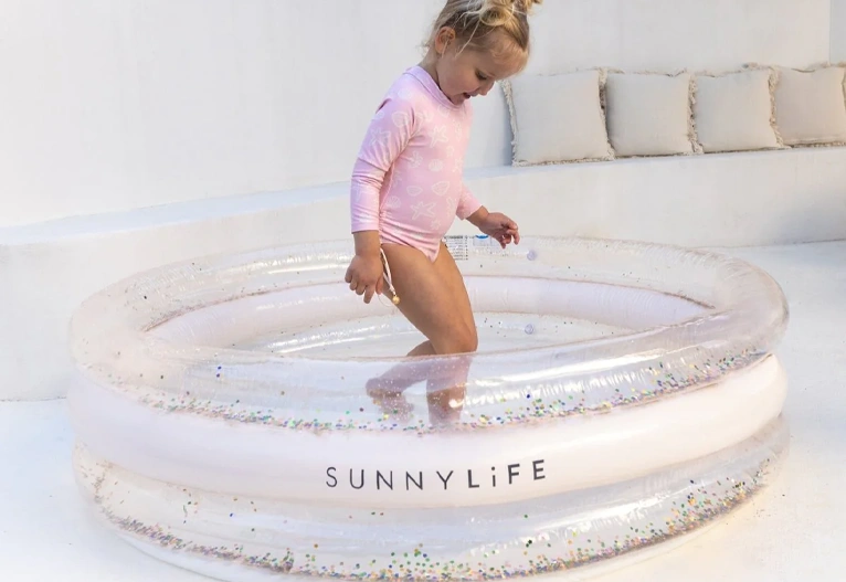 Child playing in a glitter paddling pool.