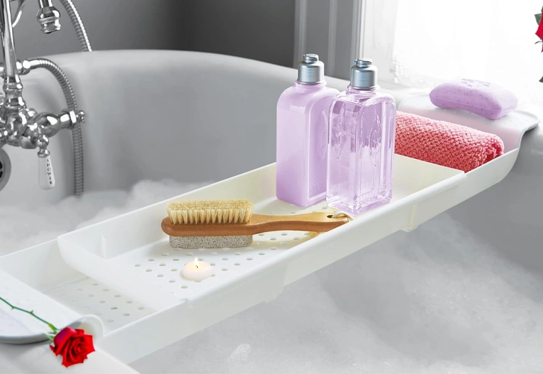 White extendable bath caddy with drainage holes.