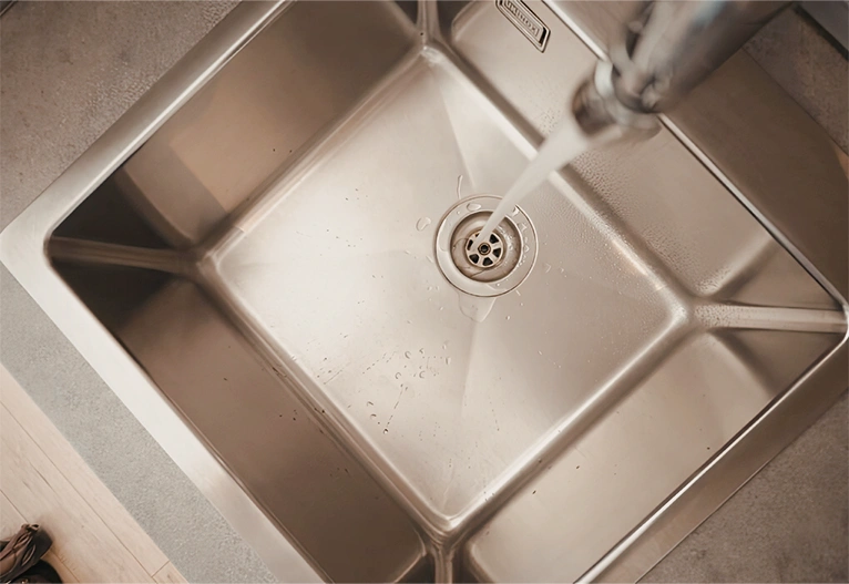 Kitchen drain with tap running.